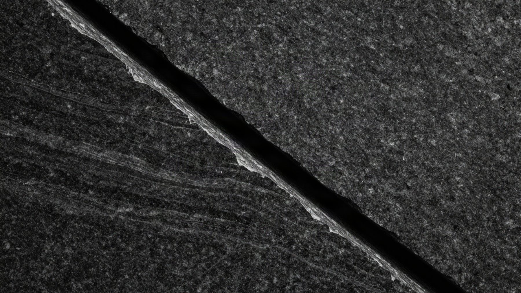 Split granite surface with layered strata under raking light