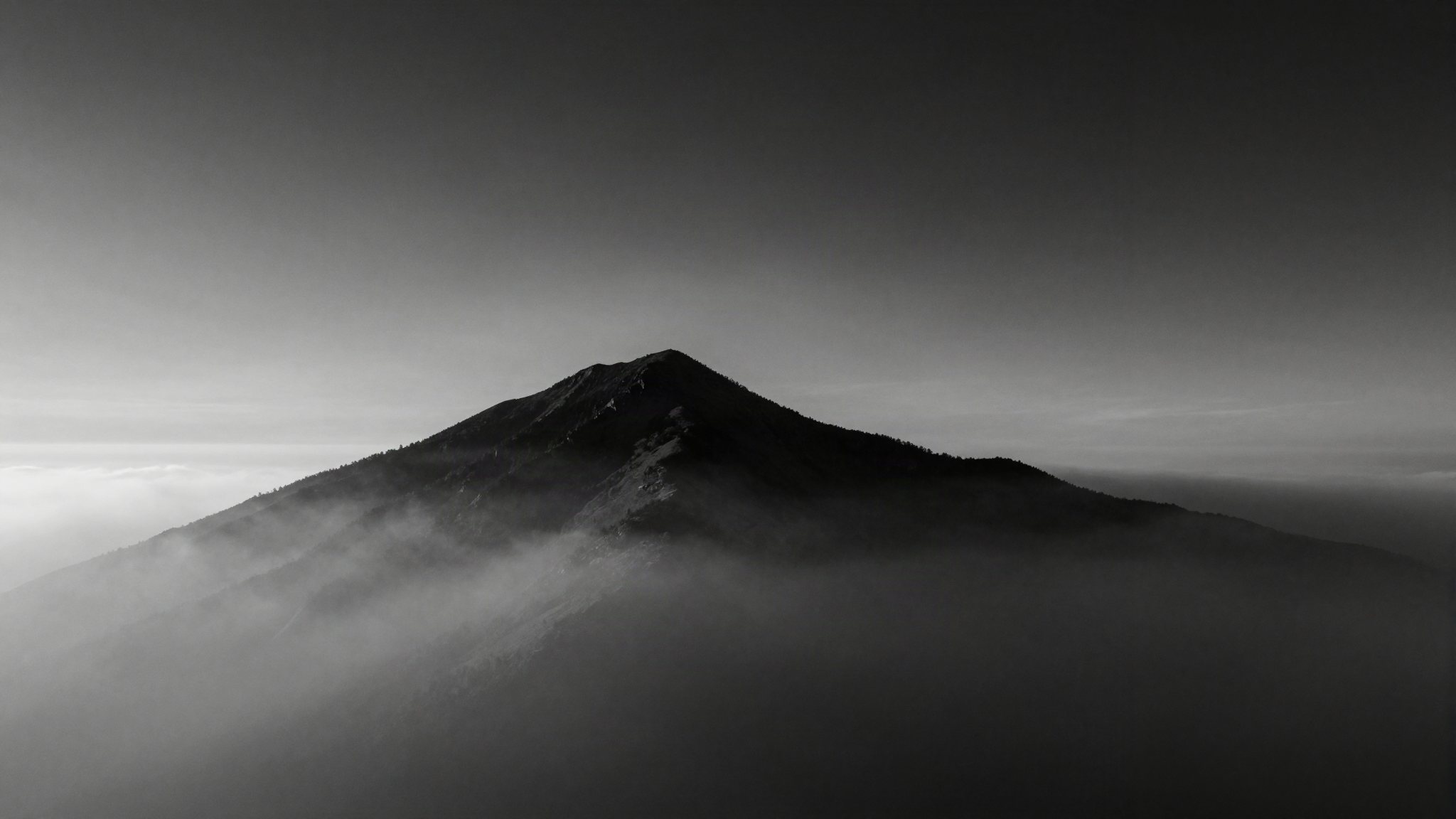 Mountain summit rising above a sea of clouds at dawn